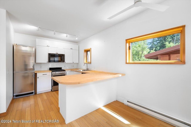 kitchen featuring a baseboard heating unit, kitchen peninsula, sink, appliances with stainless steel finishes, and white cabinets