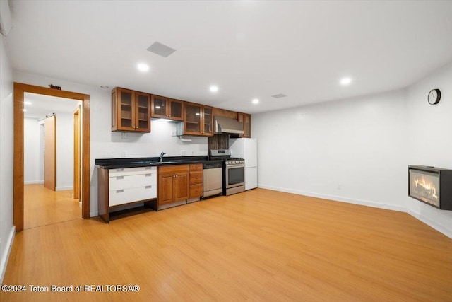 kitchen featuring backsplash, light hardwood / wood-style floors, sink, stainless steel appliances, and wall chimney exhaust hood