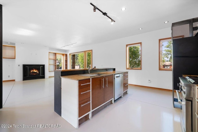 kitchen featuring sink, rail lighting, stainless steel appliances, and a healthy amount of sunlight