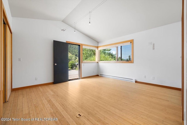 spare room featuring light hardwood / wood-style floors, a baseboard heating unit, and lofted ceiling