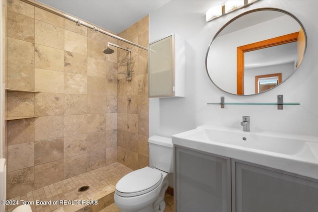 bathroom featuring toilet, tiled shower, and vanity