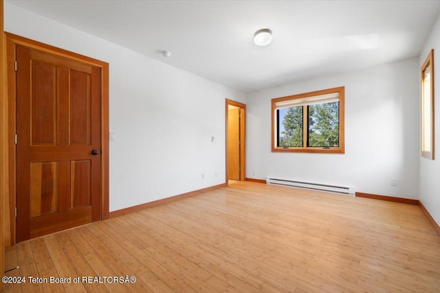 empty room with baseboard heating and light hardwood / wood-style flooring