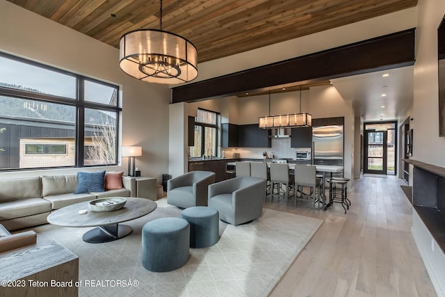 living room featuring sink, wooden ceiling, an inviting chandelier, and light hardwood / wood-style flooring