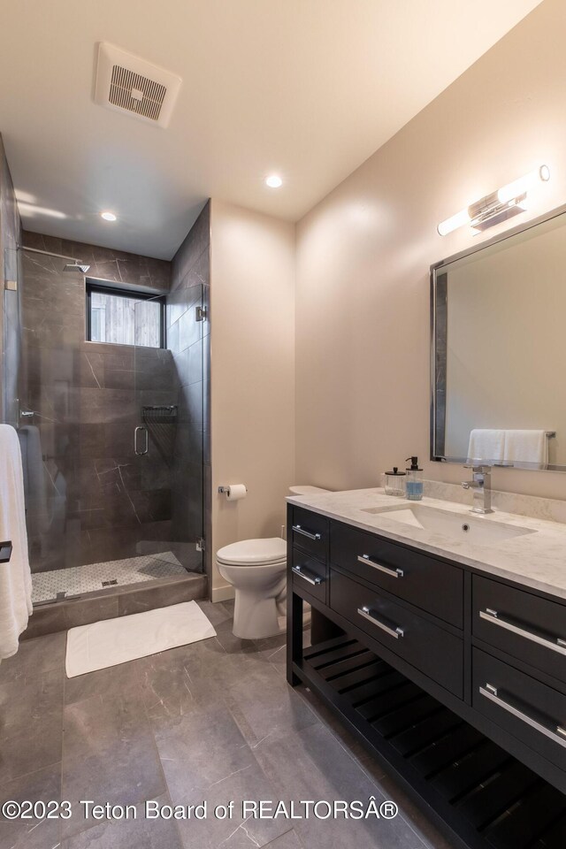 bathroom featuring a shower with door, vanity, and toilet