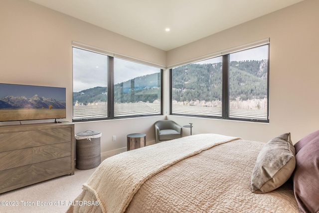 carpeted bedroom featuring a mountain view and multiple windows