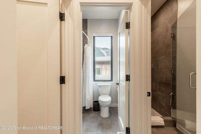 bathroom featuring toilet and a shower with door