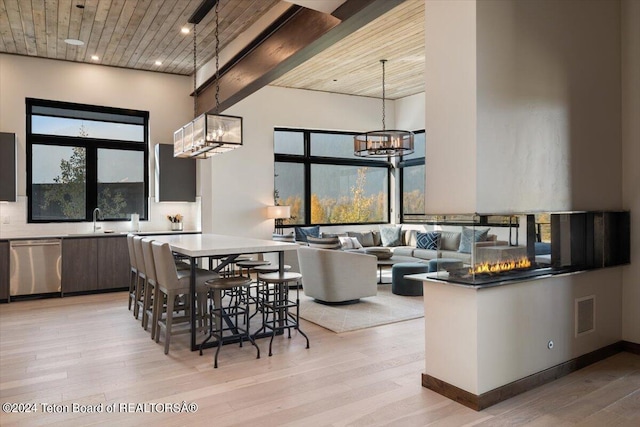 interior space with sink, decorative light fixtures, light wood-type flooring, stainless steel dishwasher, and backsplash