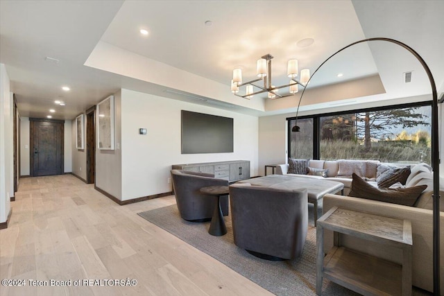 living room featuring a chandelier, a tray ceiling, and light hardwood / wood-style floors