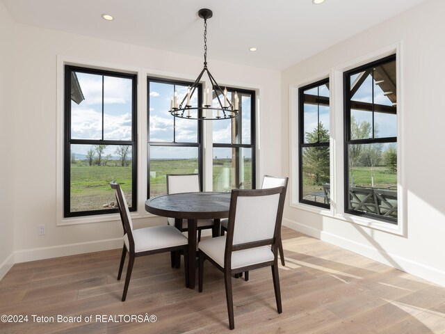 dining space with wood-type flooring, an inviting chandelier, and a wealth of natural light