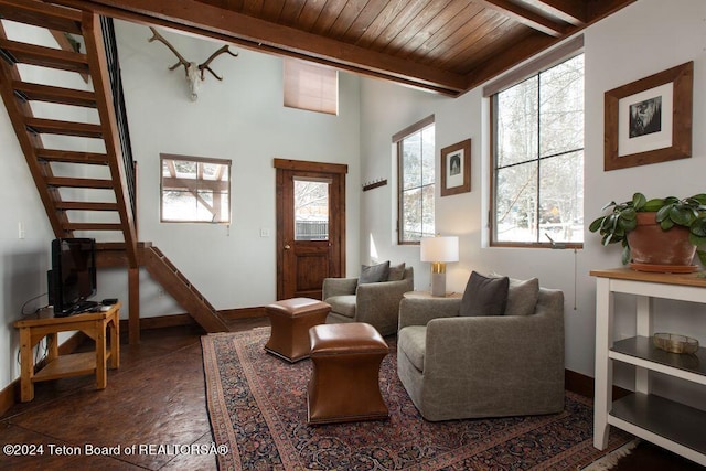 living area featuring stairs, beamed ceiling, wood ceiling, and baseboards