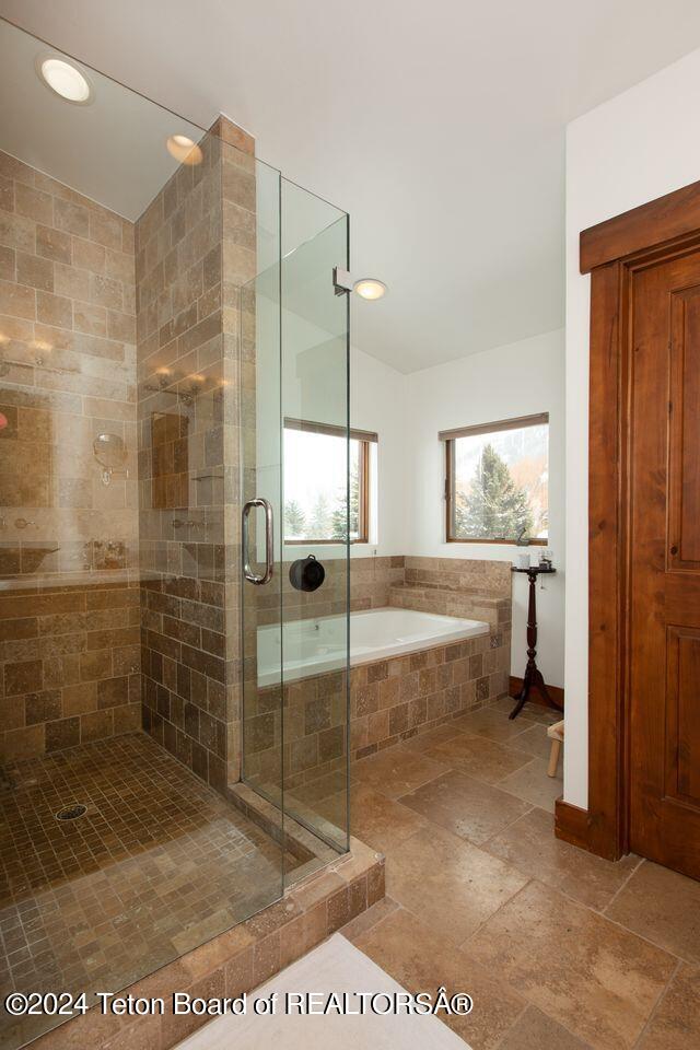 bathroom featuring recessed lighting, a shower stall, a bath, and stone tile floors