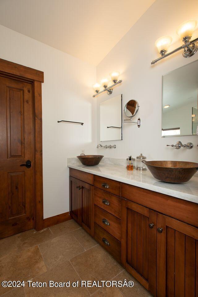 full bathroom with double vanity, baseboards, and a sink