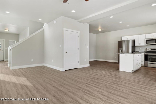 unfurnished living room featuring ceiling fan and light hardwood / wood-style flooring