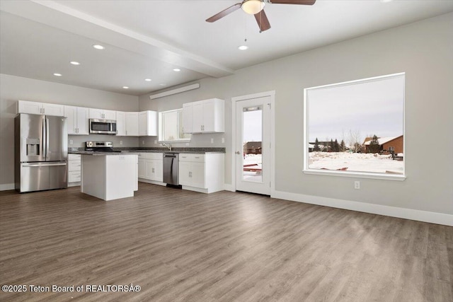 kitchen featuring dark wood-type flooring, stainless steel appliances, a center island, and white cabinets