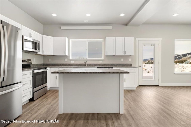 kitchen featuring stainless steel appliances, a center island, light hardwood / wood-style flooring, and white cabinets