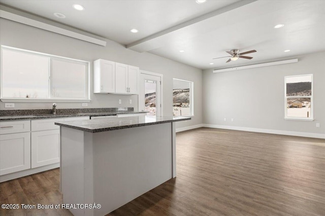 kitchen featuring dark stone countertops, sink, a kitchen island, and white cabinets