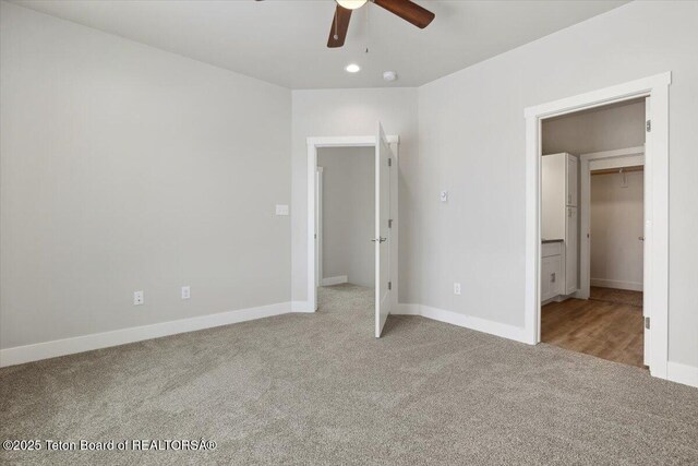 unfurnished bedroom featuring a spacious closet, light carpet, and ceiling fan