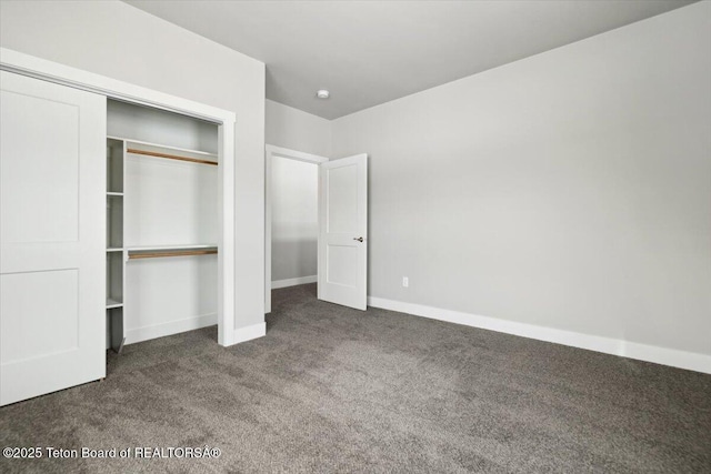 unfurnished bedroom featuring dark carpet and a closet