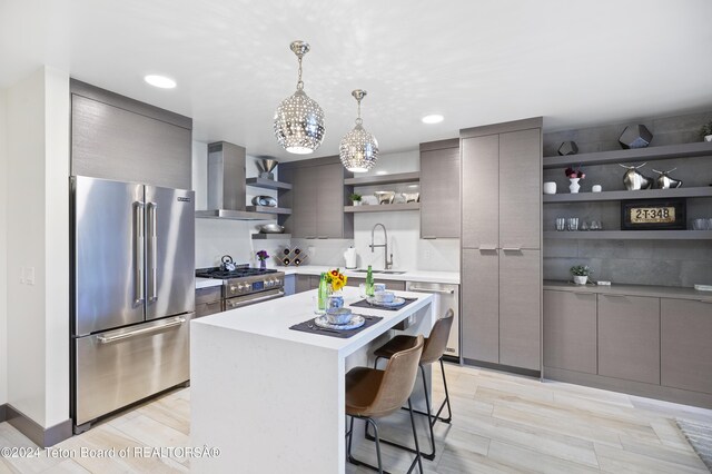 kitchen with high quality appliances, decorative backsplash, a kitchen breakfast bar, a center island, and wall chimney exhaust hood