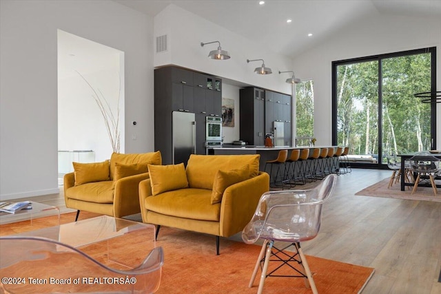 living room with high vaulted ceiling and light wood-type flooring