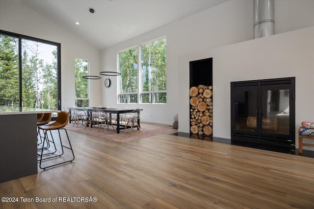 dining space with high vaulted ceiling and wood-type flooring