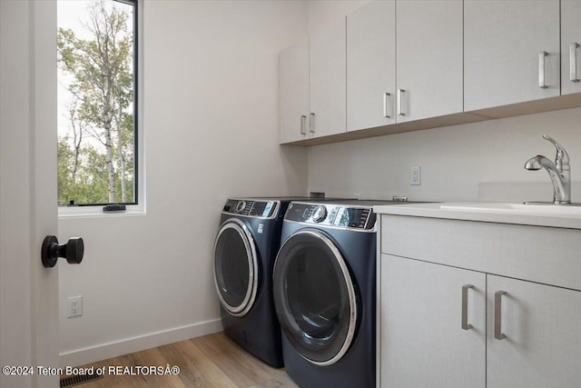 laundry area with sink, cabinets, washer and dryer, and light wood-type flooring