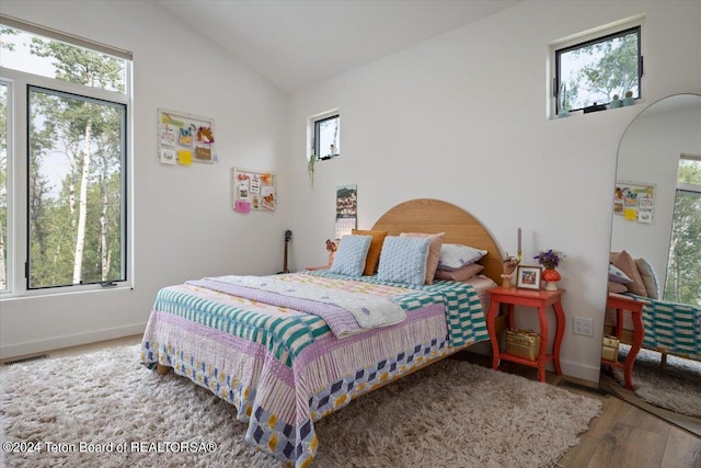 bedroom featuring multiple windows, hardwood / wood-style flooring, and vaulted ceiling