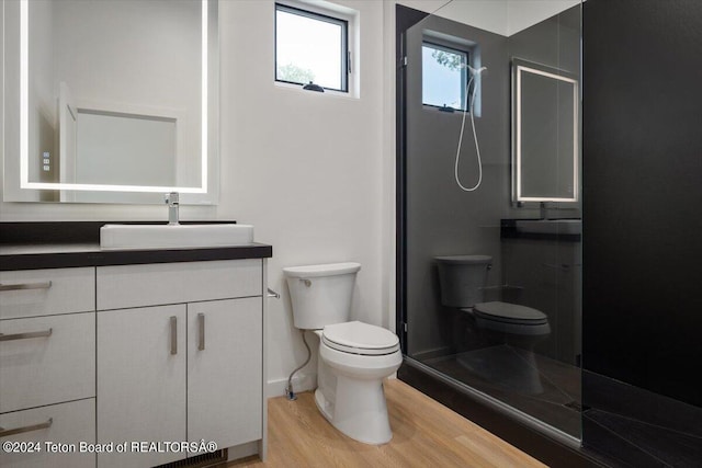 bathroom featuring hardwood / wood-style floors, a shower with door, toilet, and vanity