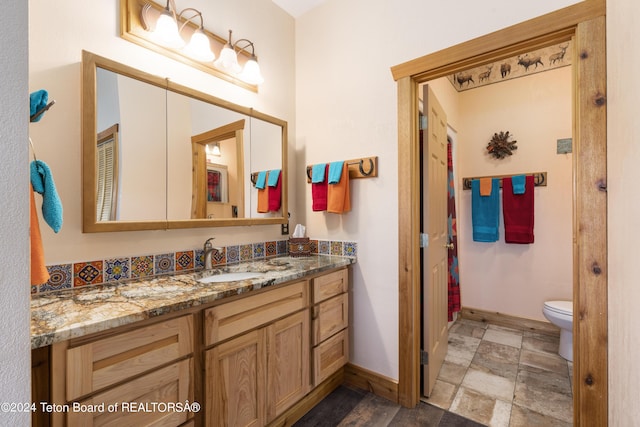 14 Table Top Dr, Dubois, WY 82513 - bathroom featuring baseboards, vanity, toilet, and stone finish floors