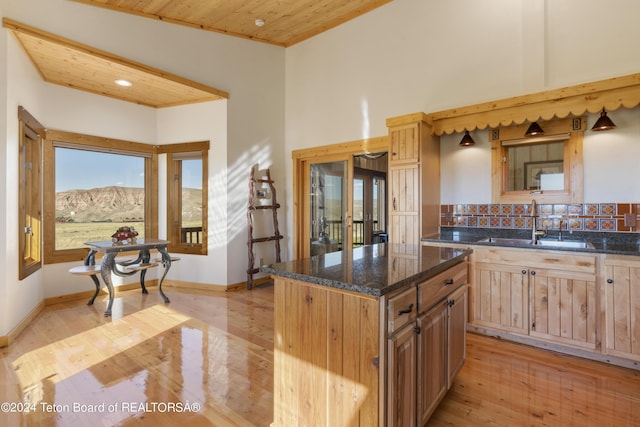 28 Table Top Dr, Dubois, WY 82513 - kitchen featuring a sink, light wood finished floors, dark stone counters, a kitchen island, and light brown cabinetry