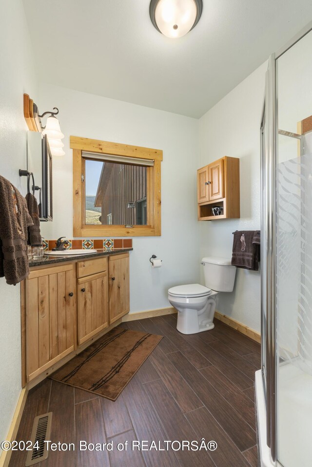 28 Table Top Dr, Dubois, WY 82513 - full bath featuring wood finished floors, toilet, vanity, a stall shower, and baseboards