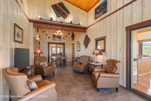 living room featuring high vaulted ceiling, wood walls, and dark tile patterned flooring