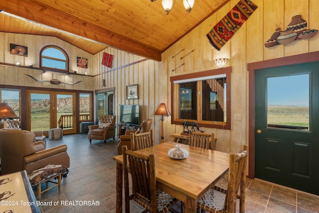 tiled dining room with plenty of natural light, wooden ceiling, wooden walls, and high vaulted ceiling