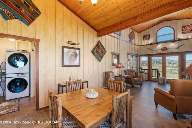 tiled dining room with stacked washer and dryer, wooden ceiling, wood walls, and high vaulted ceiling