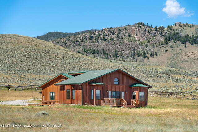 view of front of home with a deck with mountain view and a rural view