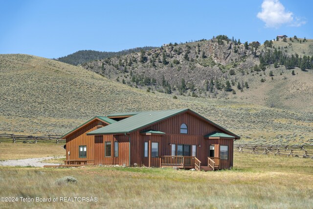 28 Table Top Dr, Dubois, WY 82513 - view of front of house with a deck with mountain view, board and batten siding, and metal roof