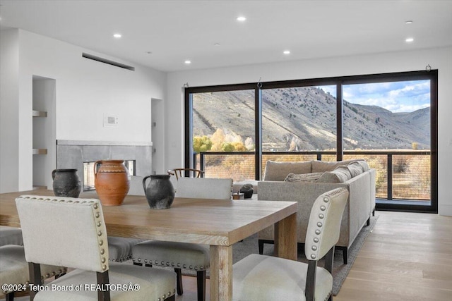 dining space featuring a mountain view, a healthy amount of sunlight, and light wood-type flooring