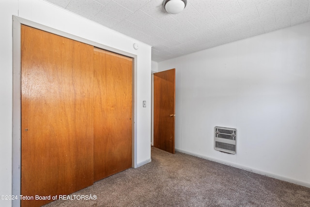 unfurnished bedroom with carpet, a closet, and heating unit