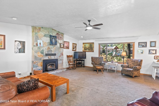 living room with ceiling fan, a textured ceiling, carpet, lofted ceiling, and a stone fireplace