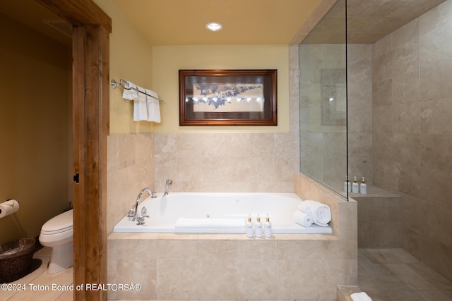 bathroom featuring tiled bath, tile patterned flooring, and toilet