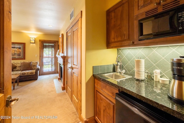 kitchen featuring dark stone countertops, sink, backsplash, stainless steel dishwasher, and light carpet