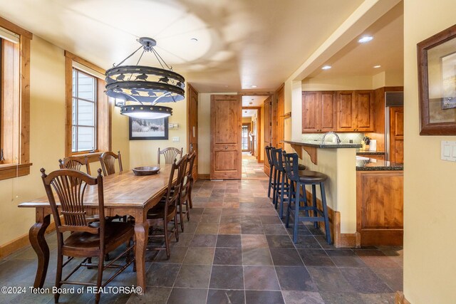 dining area featuring dark tile patterned floors, sink, and a chandelier