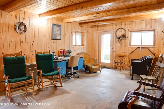 sitting room with beam ceiling, wood walls, wooden ceiling, and concrete floors