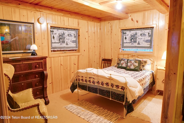 bedroom with beam ceiling and wooden walls