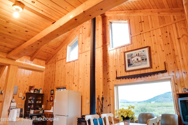 room details with beamed ceiling, wooden ceiling, white refrigerator, and wood walls