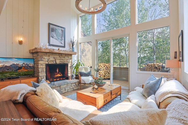 living area featuring a notable chandelier, a stone fireplace, and a towering ceiling