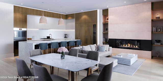 dining space with built in features, a fireplace, sink, and light hardwood / wood-style floors