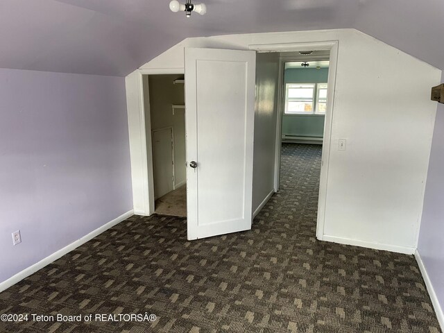 additional living space featuring lofted ceiling, baseboard heating, and dark colored carpet