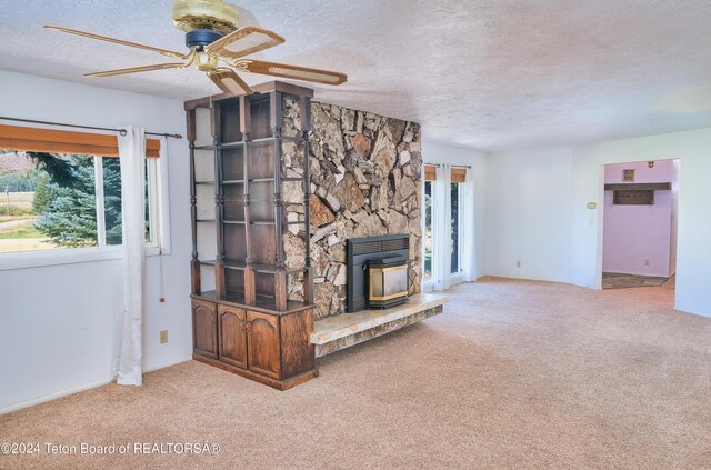 unfurnished living room with a textured ceiling, plenty of natural light, ceiling fan, and a fireplace