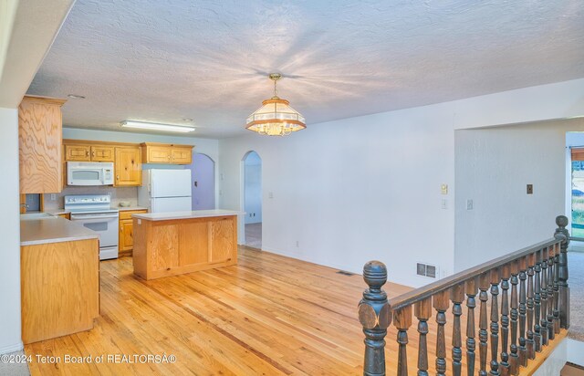 kitchen with hanging light fixtures, light wood-type flooring, white appliances, a chandelier, and sink